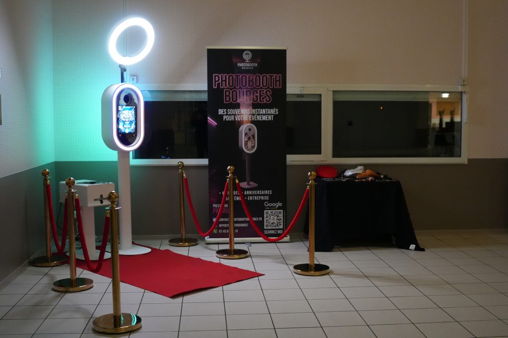 Installation du photobooth moderne avec tapis rouge, éclairage et espace accessoires dans une salle de réception.